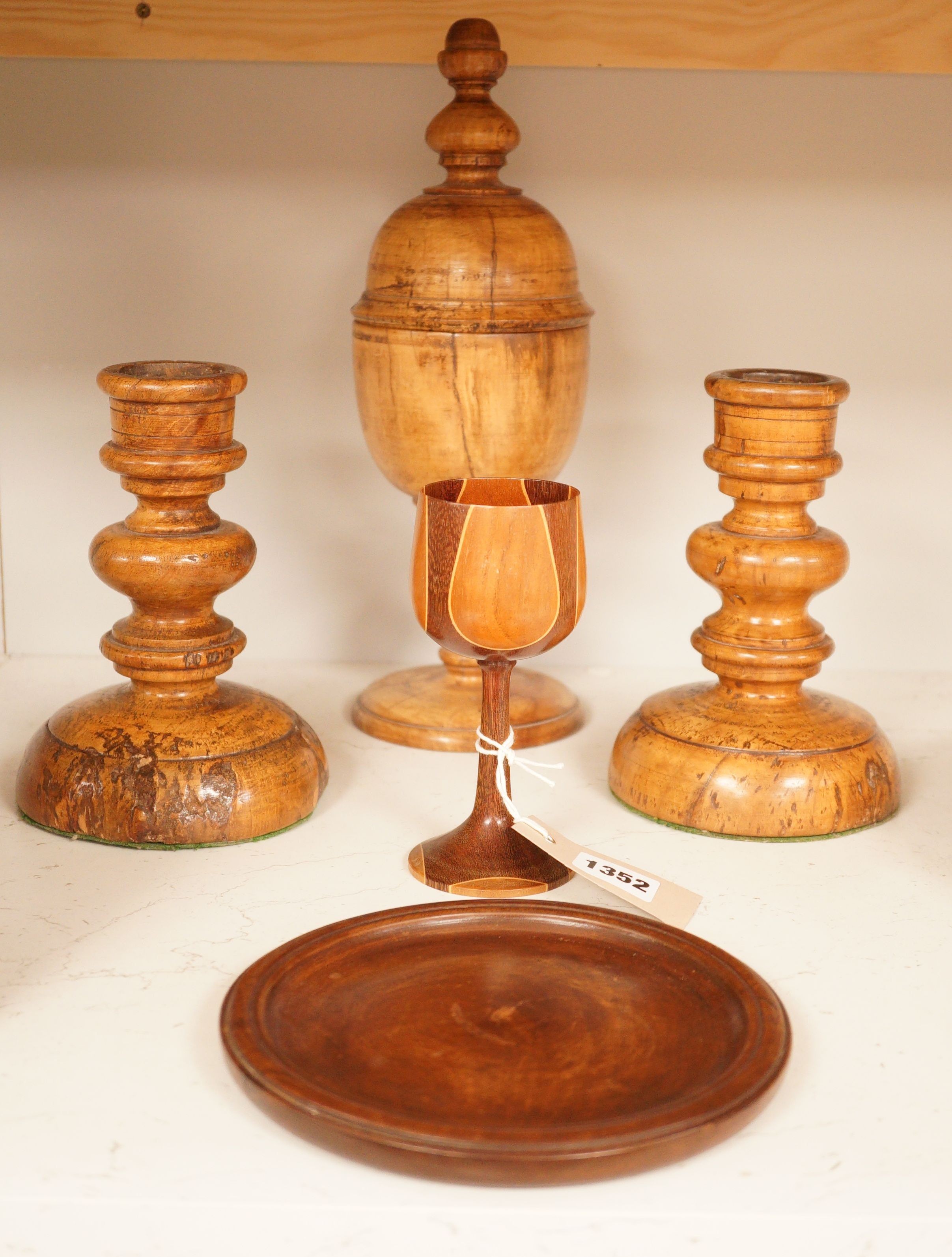 A treen goblet and cover, two candlesticks, a cup and a coaster